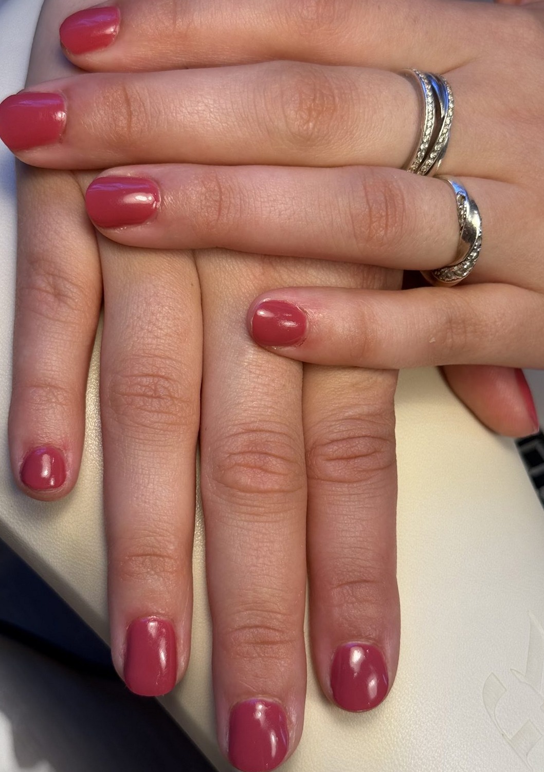 Hand met frambozenrode gellak en zilveren ringen