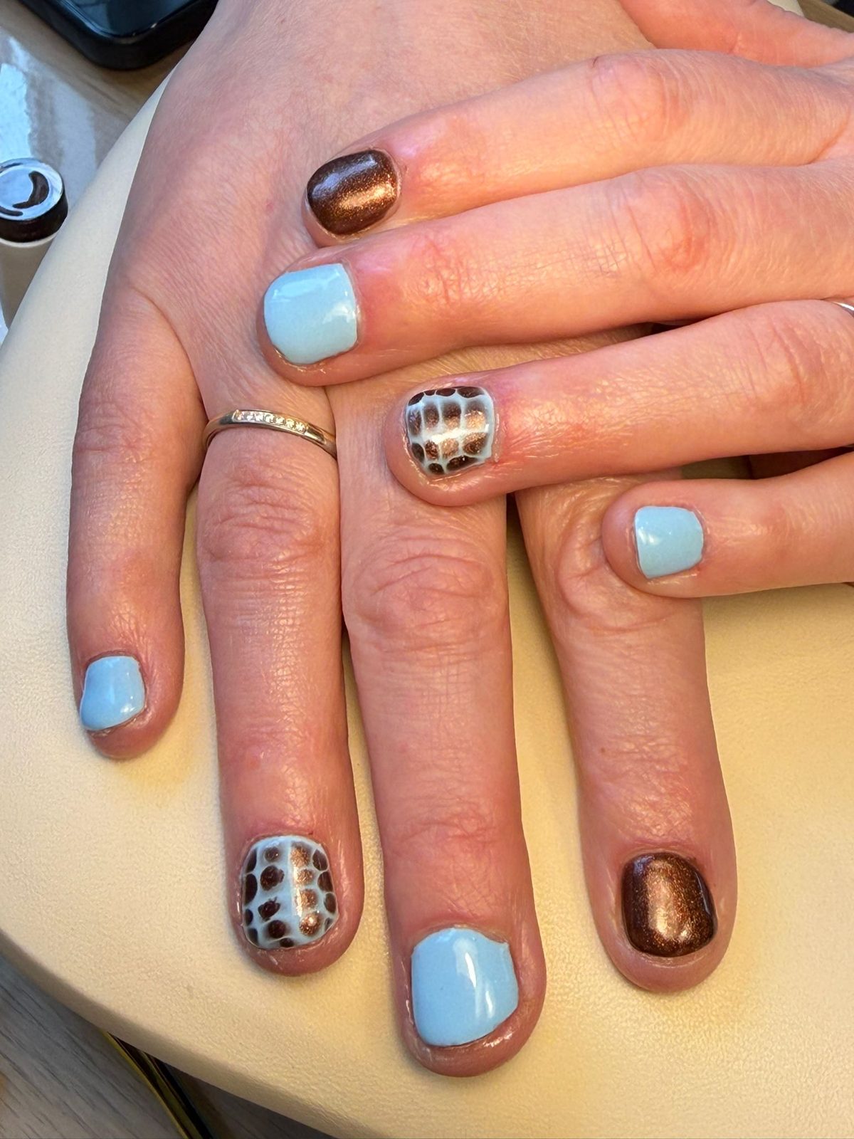 Lichtblauwe nagels met bruine chrome en een geruit nail art design